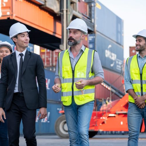 Group of cargo container workers or factory and engineer technicians walk and discuss together in workplace area. Concept of good teamwork support best success work of industrial business.